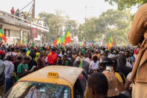 People on the streets of dakar, senegal behind a taxi matching in celebration with senegales flags